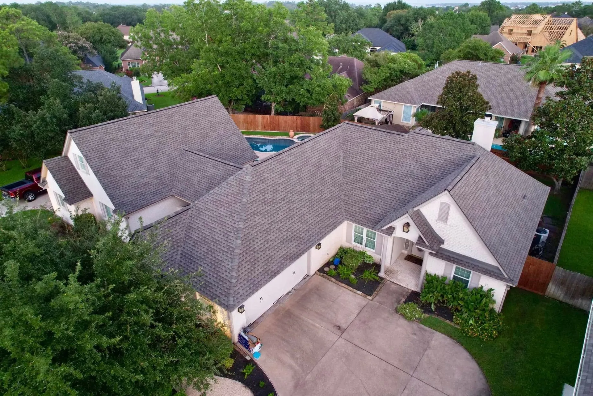 Aerial view of a North Houston home with a gray architectural shingle roof and a backyard pool